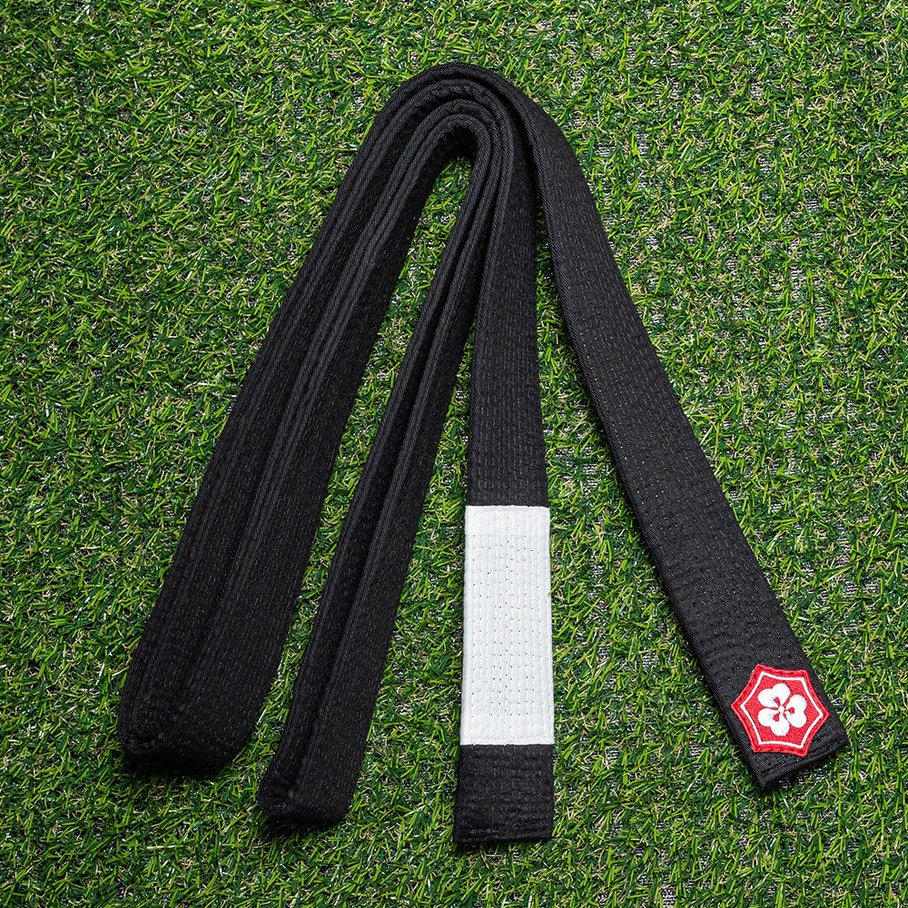 Black KANJI Classic BJJ belt with a white rank bar on training turf