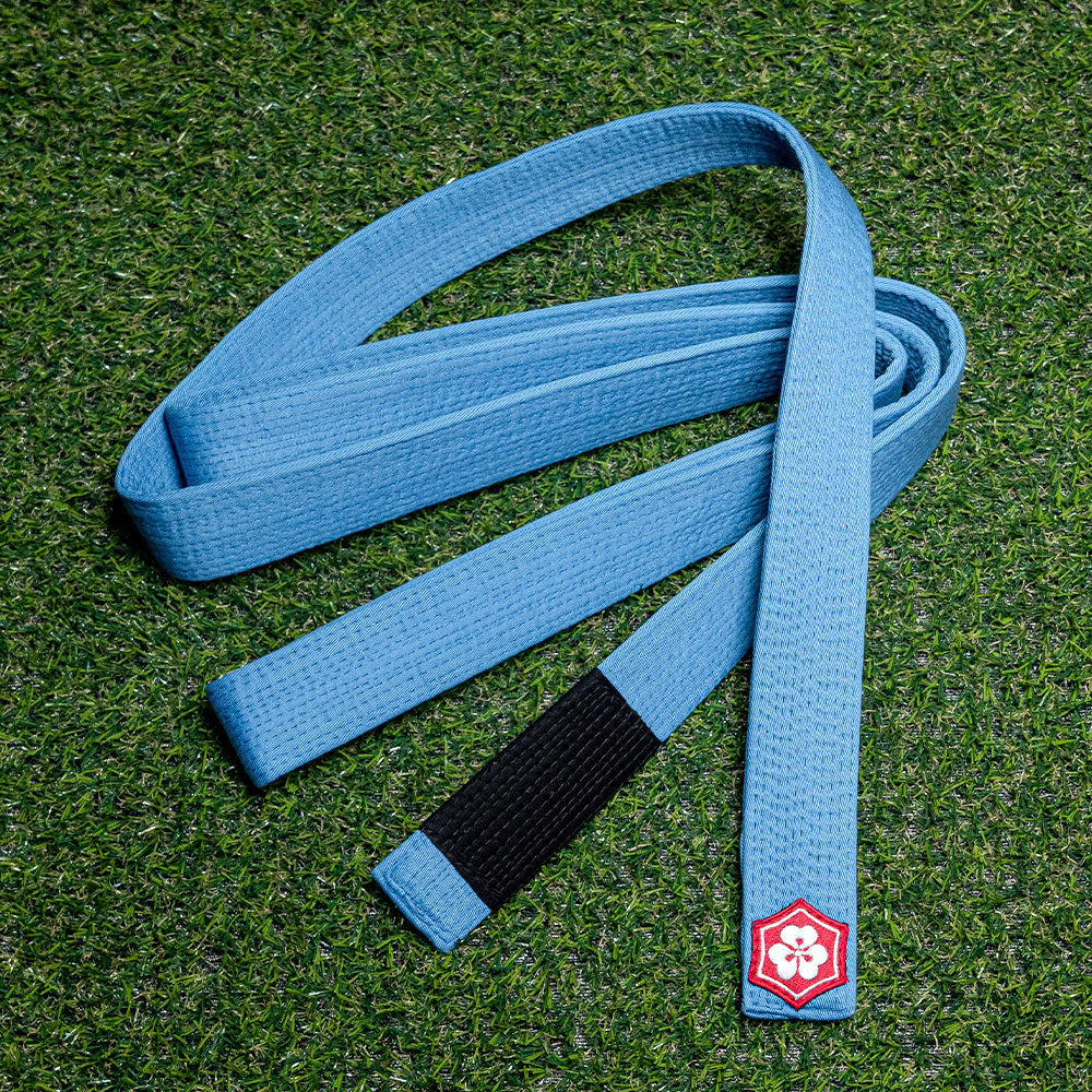 Blue KANJI Classic BJJ belt with a black rank bar on training turf
