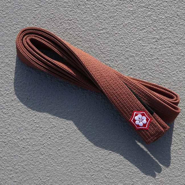 Brown KANJI KAZE BJJ belt folded on concrete