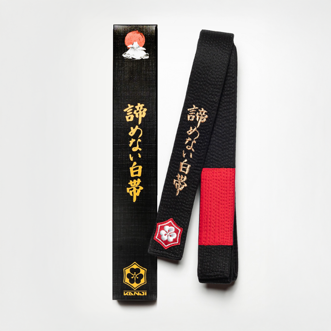 A WHITE BELT WHO NEVER QUIT EDITION — CLASSIC black belt with red bar and gold embroidery